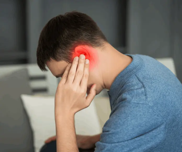 Man covering his ears in discomfort due to tinnitus or ringing in the ears